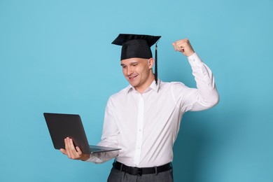 Photo of Happy student with laptop after graduation on light blue background