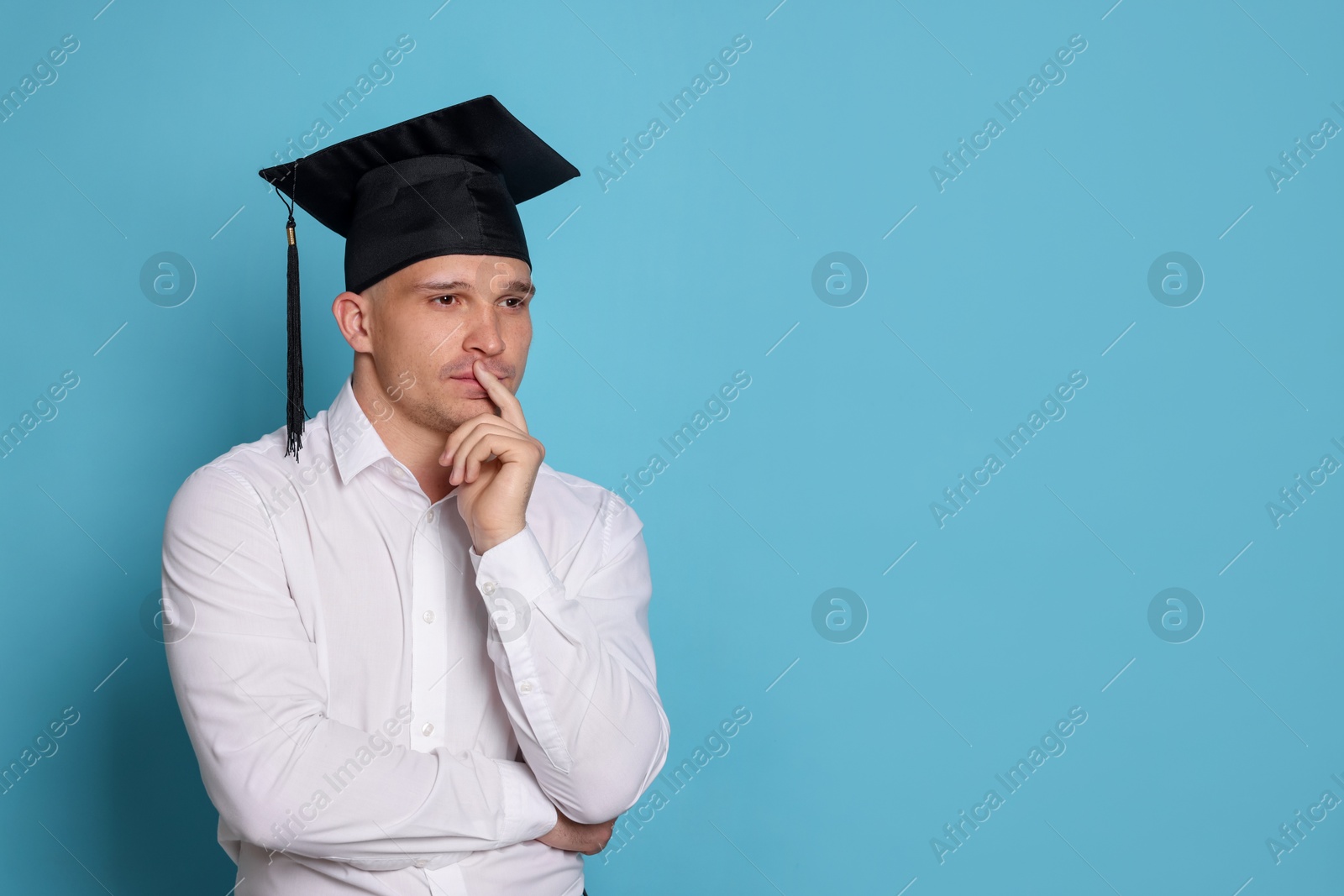Thoughtful student after graduation on light blue background. Space for text Photo of Thoughtful student after graduation on light blue background. Space for text
