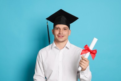 Photo of Happy student with diploma after graduation on light blue background