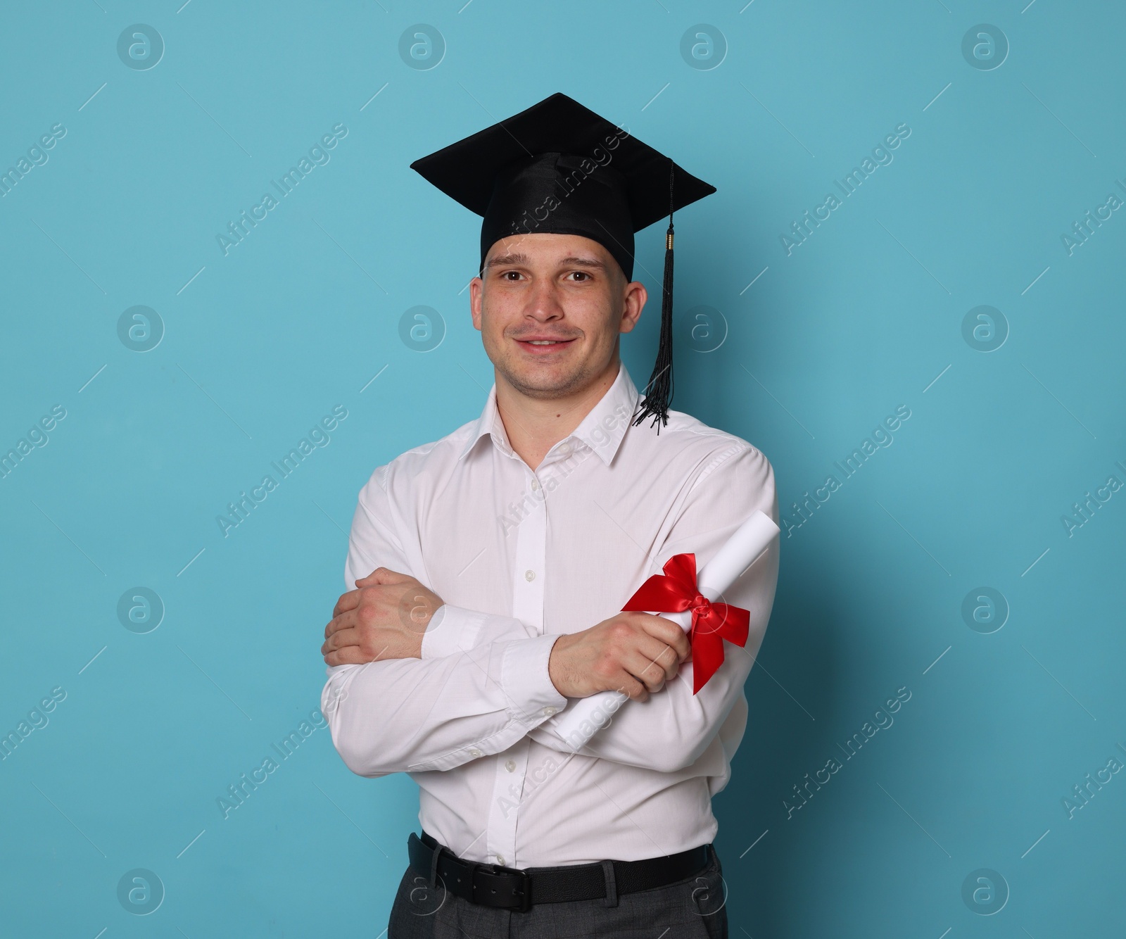 Happy student with diploma after graduation on light blue background Photo of Happy student with diploma after graduation on light blue background