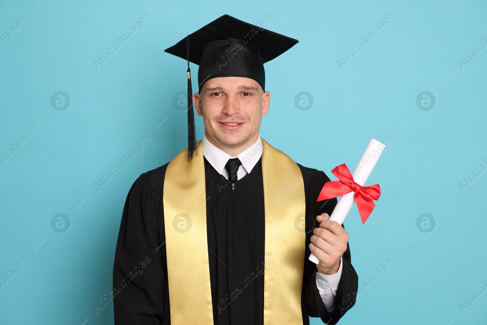 Happy student with diploma after graduation on light blue background Photo of Happy student with diploma after graduation on light blue background