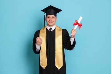 Photo of Happy student with diploma after graduation on light blue background
