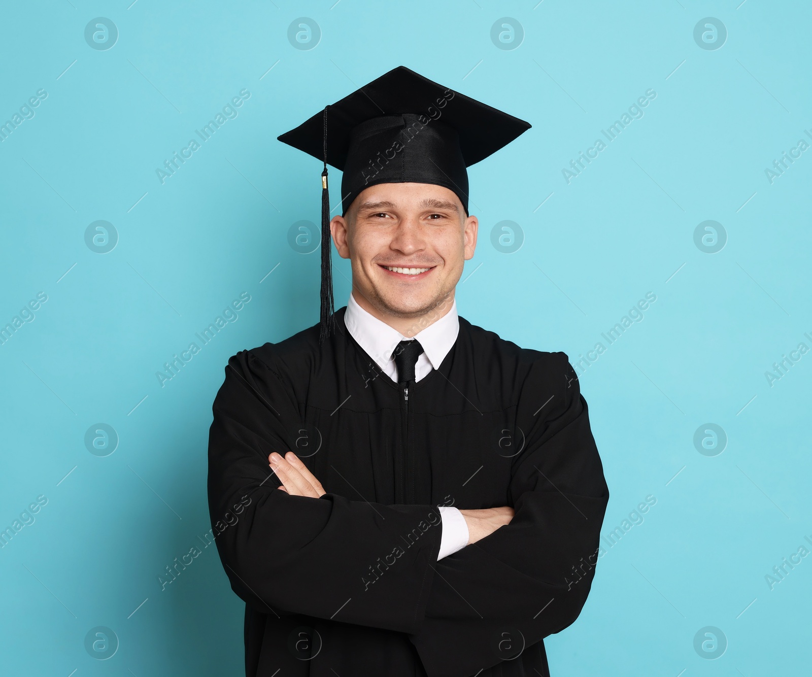 Happy student after graduation on light blue background Photo of Happy student after graduation on light blue background