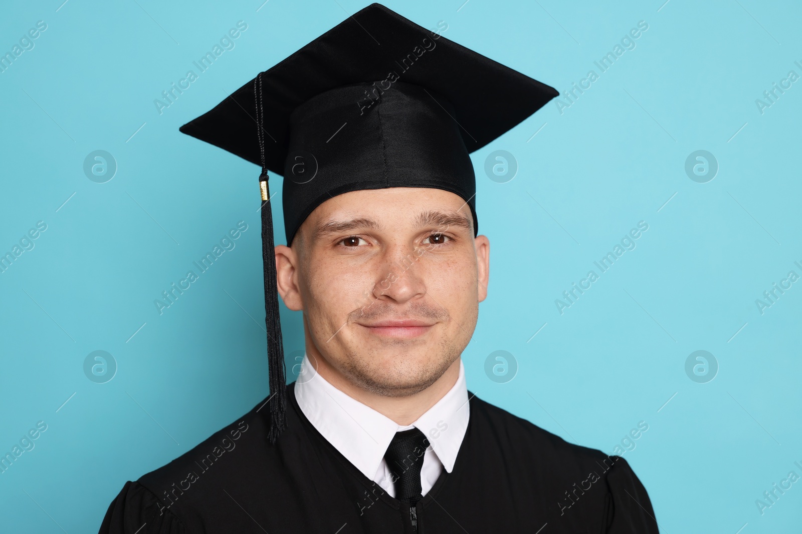 Portrait of student after graduation on light blue background Photo of Portrait of student after graduation on light blue background