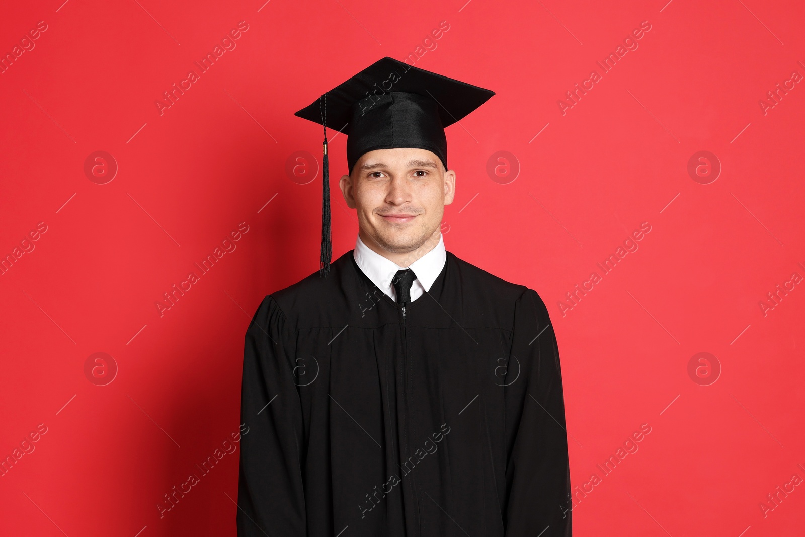Portrait of student after graduation on red background Photo of Portrait of student after graduation on red background