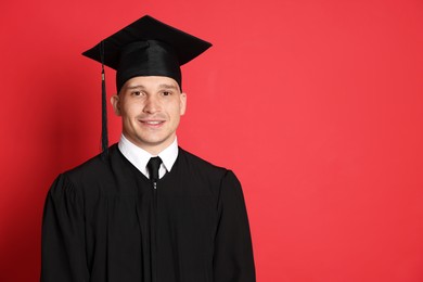 Photo of Happy student after graduation on red background. Space for text