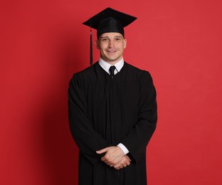 Photo of Happy student after graduation on red background