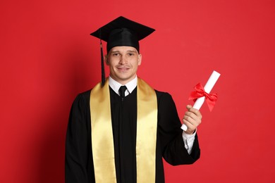 Photo of Happy student with diploma after graduation on red background