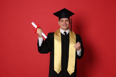 Photo of Happy student with diploma after graduation on red background