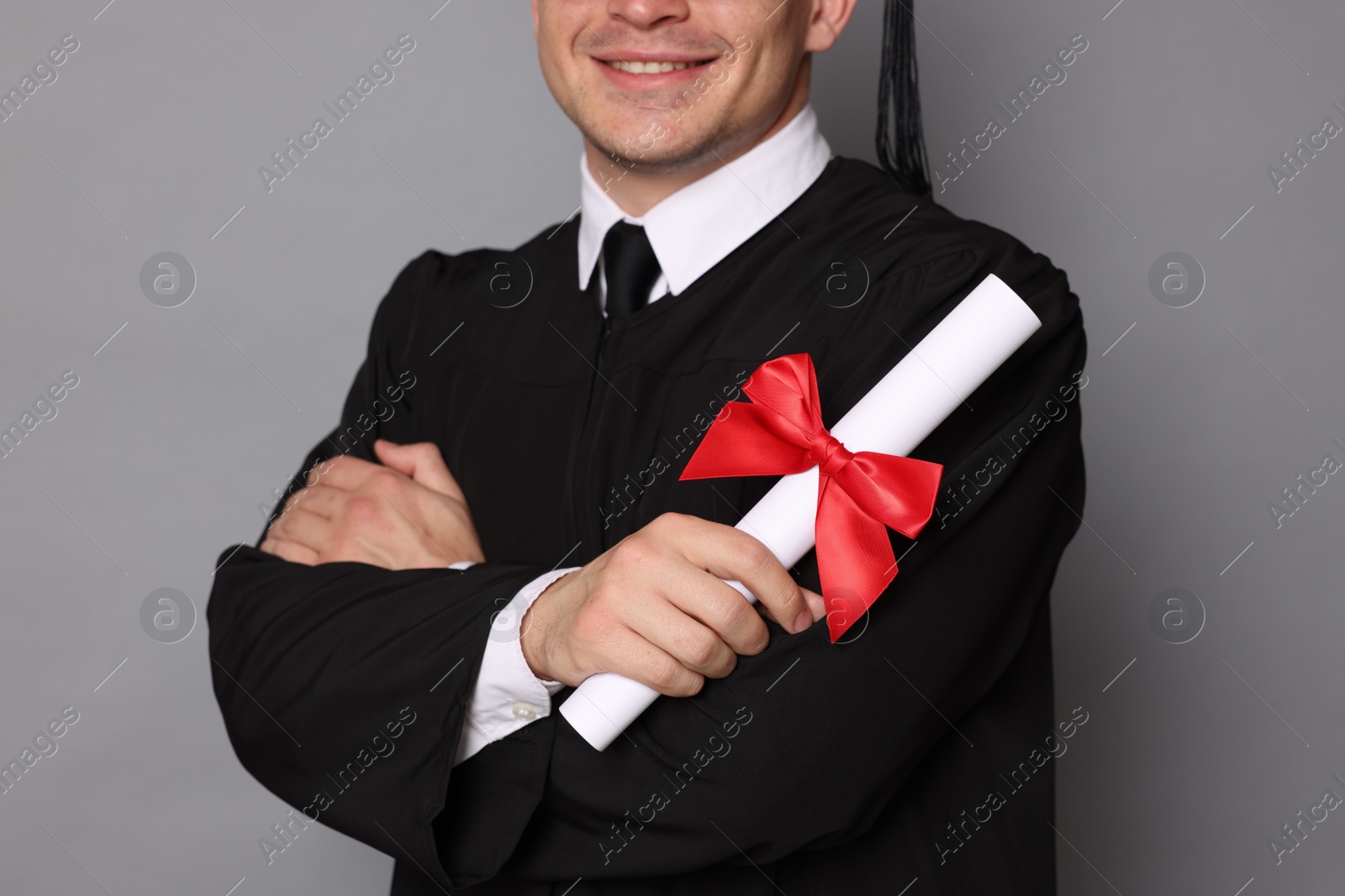 Happy student with diploma after graduation on grey background, closeup Photo of Happy student with diploma after graduation on grey background, closeup