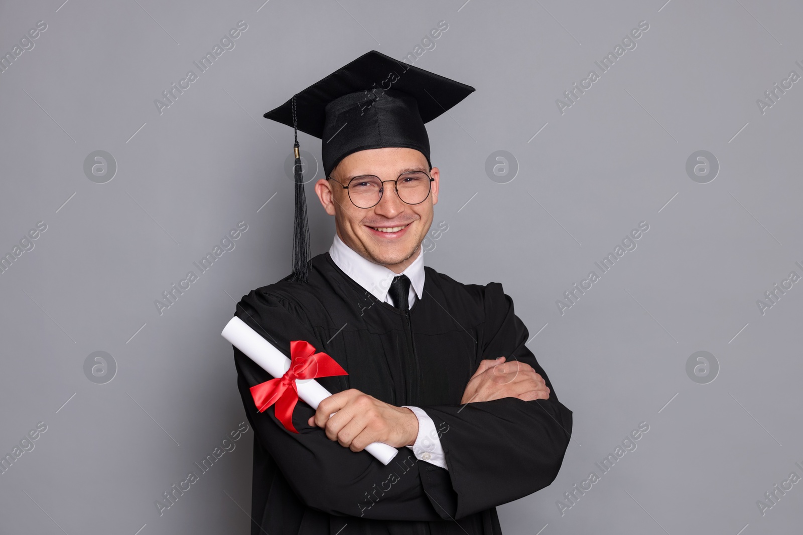 Happy student with diploma after graduation on grey background Photo of Happy student with diploma after graduation on grey background