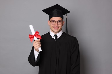 Photo of Happy student with diploma after graduation on grey background