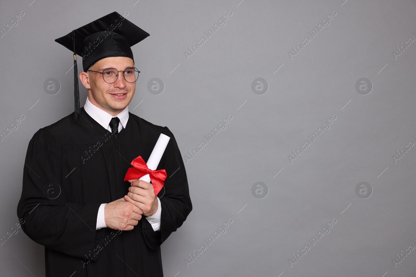Happy student with diploma after graduation on grey background. Space for text Photo of Happy student with diploma after graduation on grey background. Space for text
