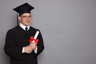 Photo of Happy student with diploma after graduation on grey background. Space for text
