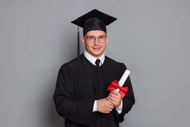 Photo of Happy student with diploma after graduation on grey background