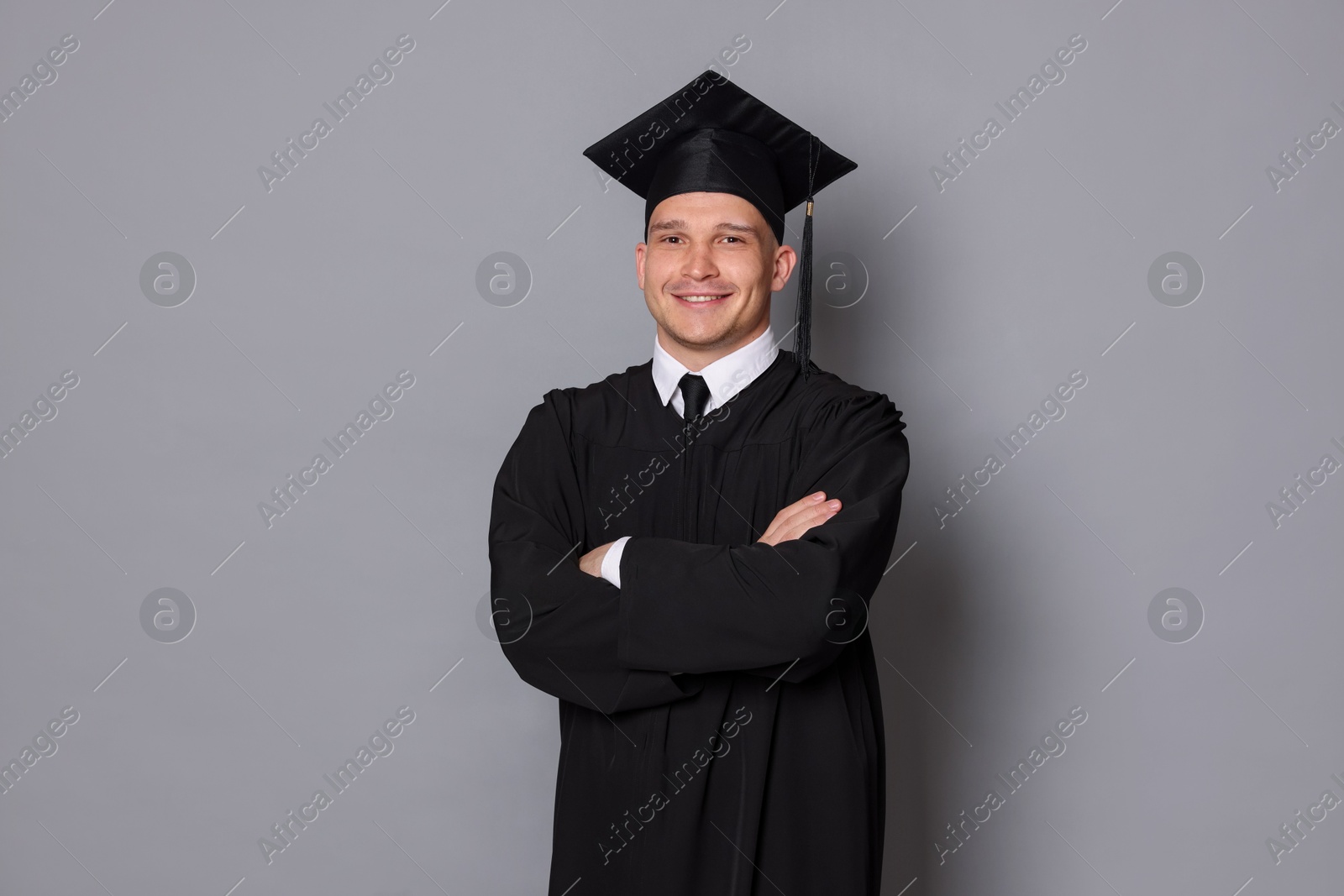 Happy student after graduation on grey background Photo of Happy student after graduation on grey background