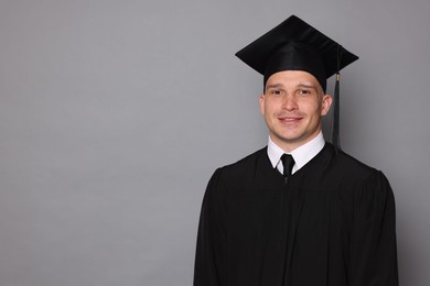 Photo of Happy student after graduation on grey background. Space for text