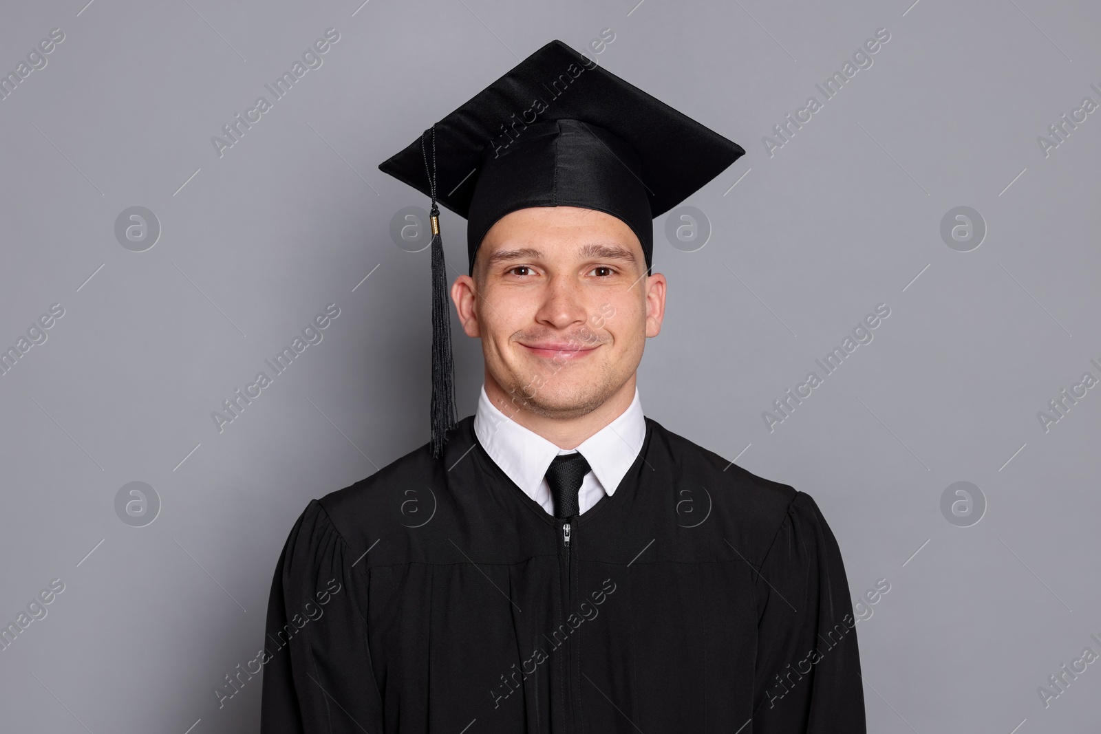 Portrait of student after graduation on grey background Photo of Portrait of student after graduation on grey background
