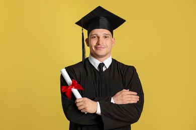 Photo of Student with diploma after graduation on yellow background