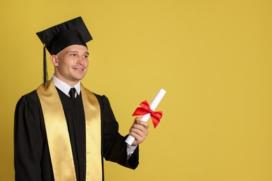 Photo of Happy student with diploma after graduation on yellow background. Space for text