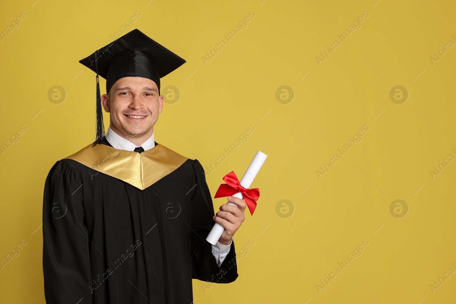Happy student with diploma after graduation on yellow background. Space for text Photo of Happy student with diploma after graduation on yellow background. Space for text