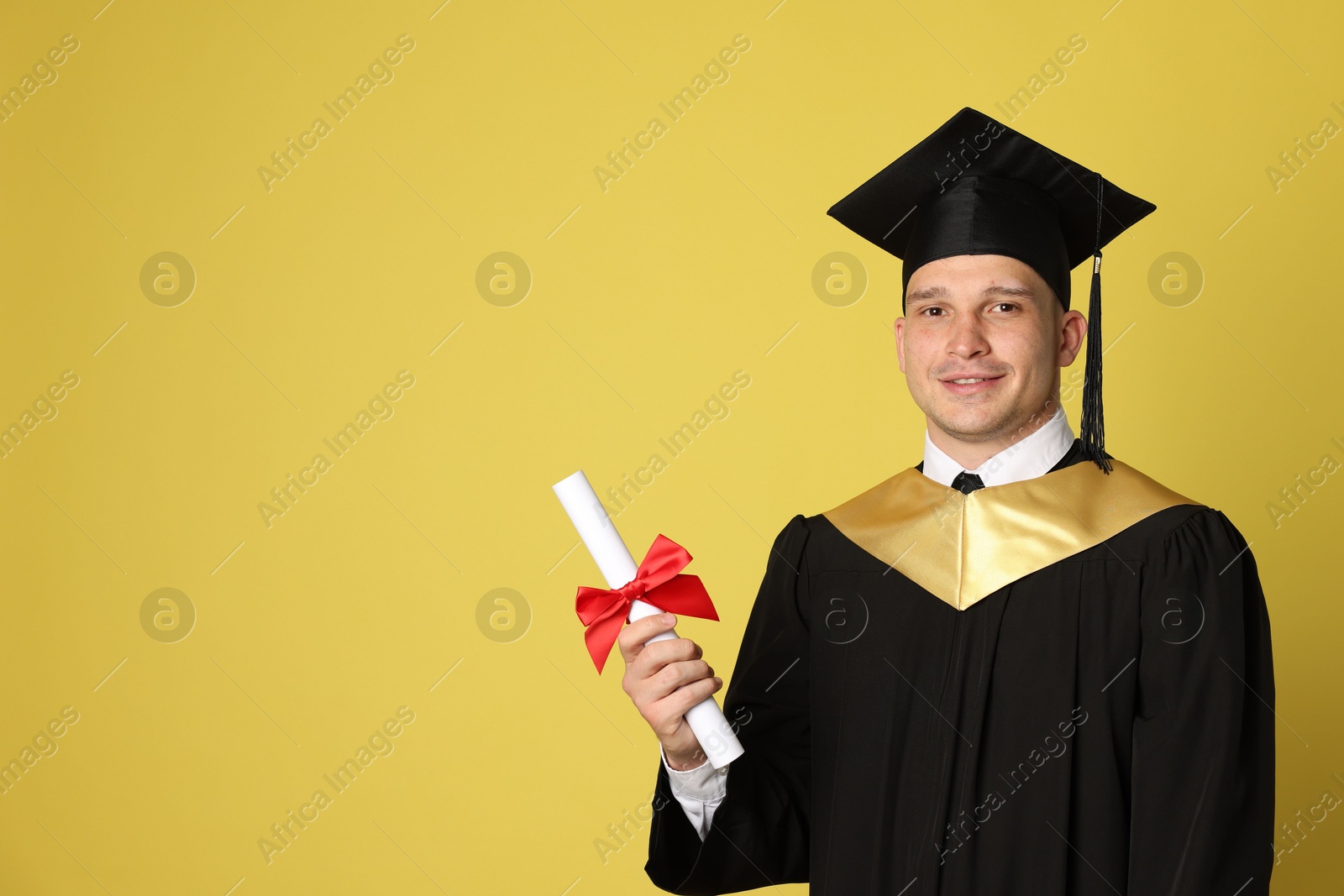 Happy student with diploma after graduation on yellow background. Space for text Photo of Happy student with diploma after graduation on yellow background. Space for text