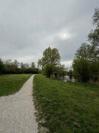 Photo of View of pathway alongside pond in beautiful park