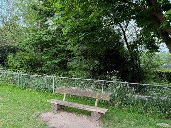 Photo of Empty wooden bench near fence in beautiful park