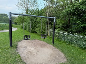 Photo of Empty swing set on playground in park