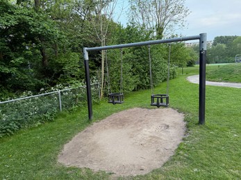 Photo of Empty swing set on playground in park
