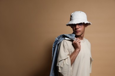 Photo of Fashionable portrait of handsome man in stylish outfit on brown background, space for text