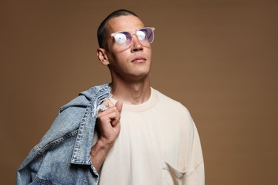 Photo of Fashionable portrait of handsome man in stylish outfit on brown background