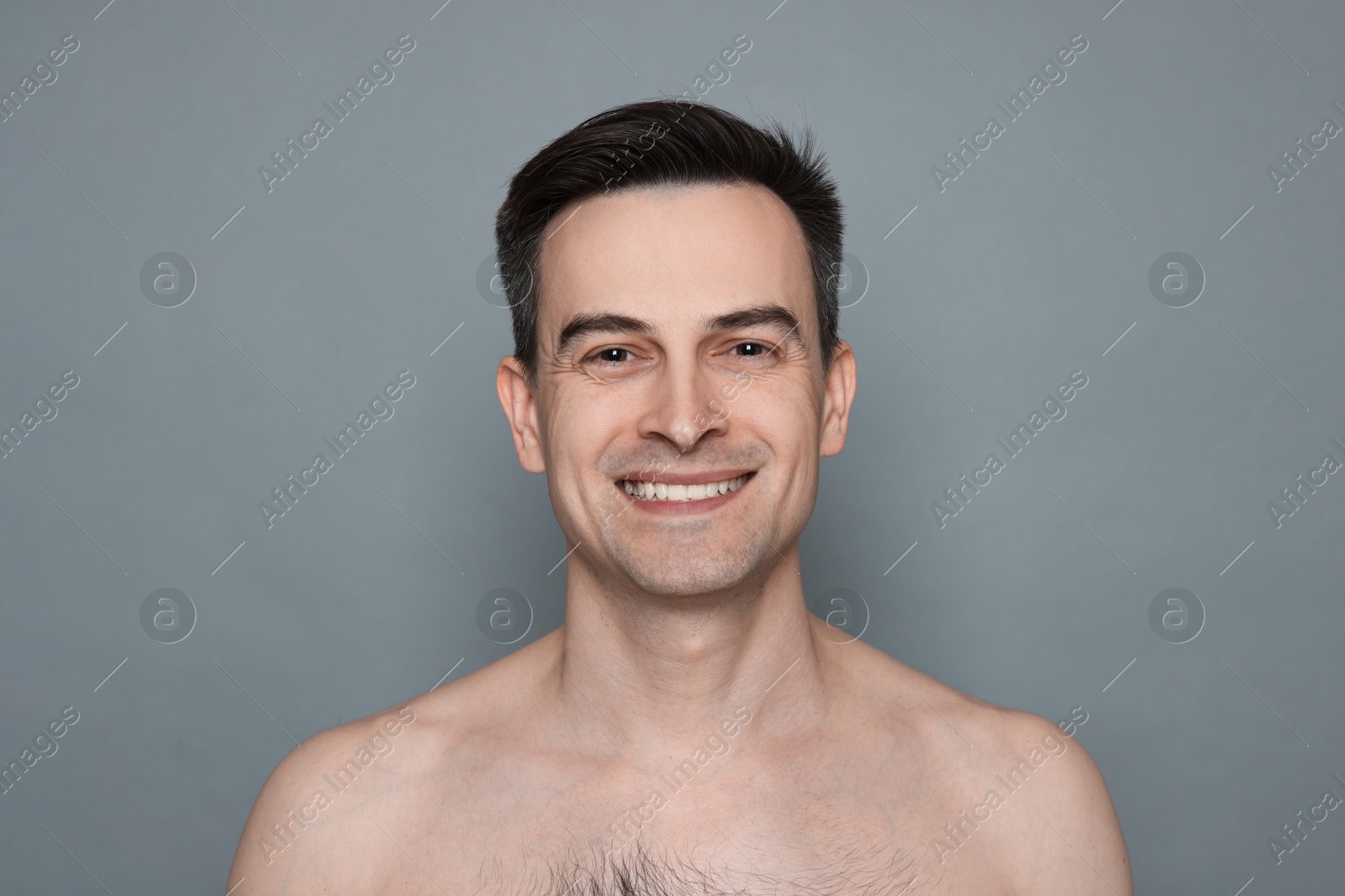 Smiling man after shaving on grey background Photo of Smiling man after shaving on grey background