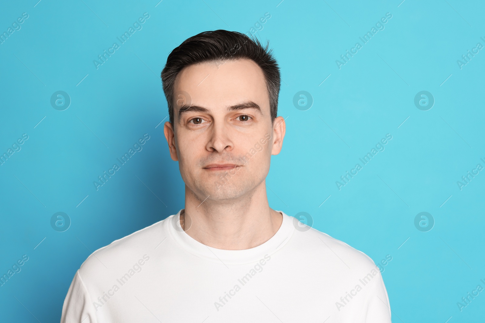 Handsome man after shaving on light blue background Photo of Handsome man after shaving on light blue background