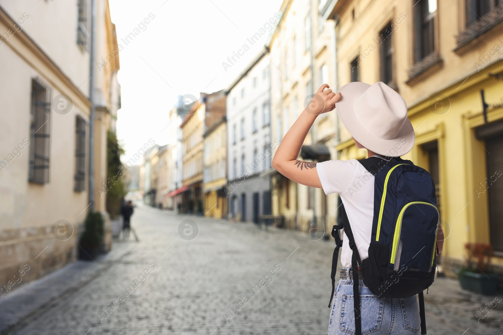 Tourist with backpack on city street, back view. Space for text Image of Tourist with backpack on city street, back view. Space for text