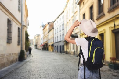Image of Tourist with backpack on city street, back view. Space for text