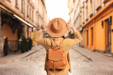 Image of Tourist with backpack on city street, back view