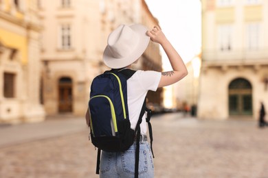 Image of Tourist with backpack on city street, back view