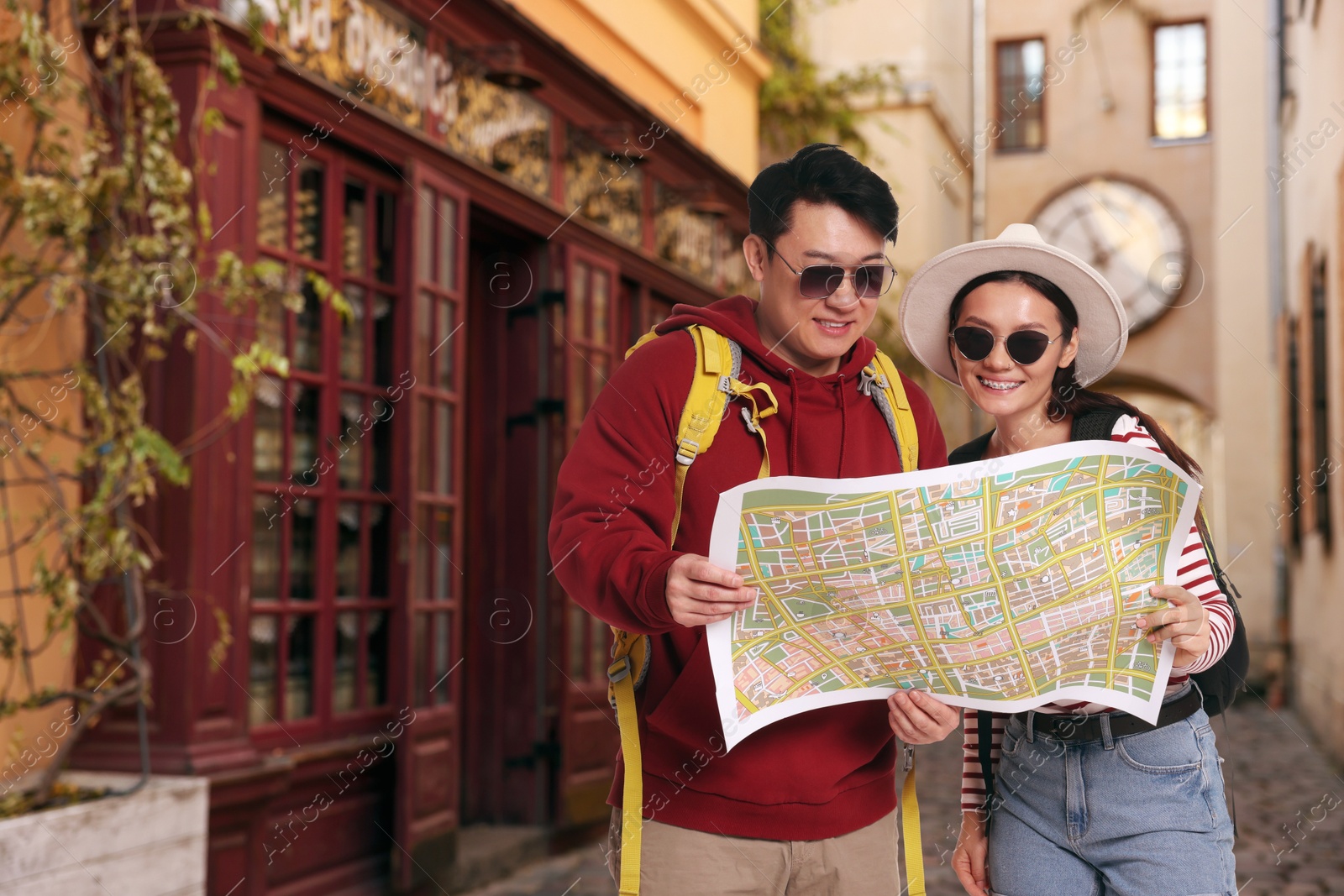 Happy tourists with map on city street. Space for text Image of Happy tourists with map on city street. Space for text