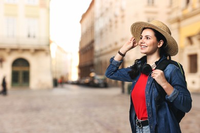 Image of Happy tourist with backpack and headphones on city street. Space for text