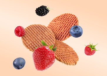 Image of Tasty Dutch waffles and fresh berries flying on beige gradient background