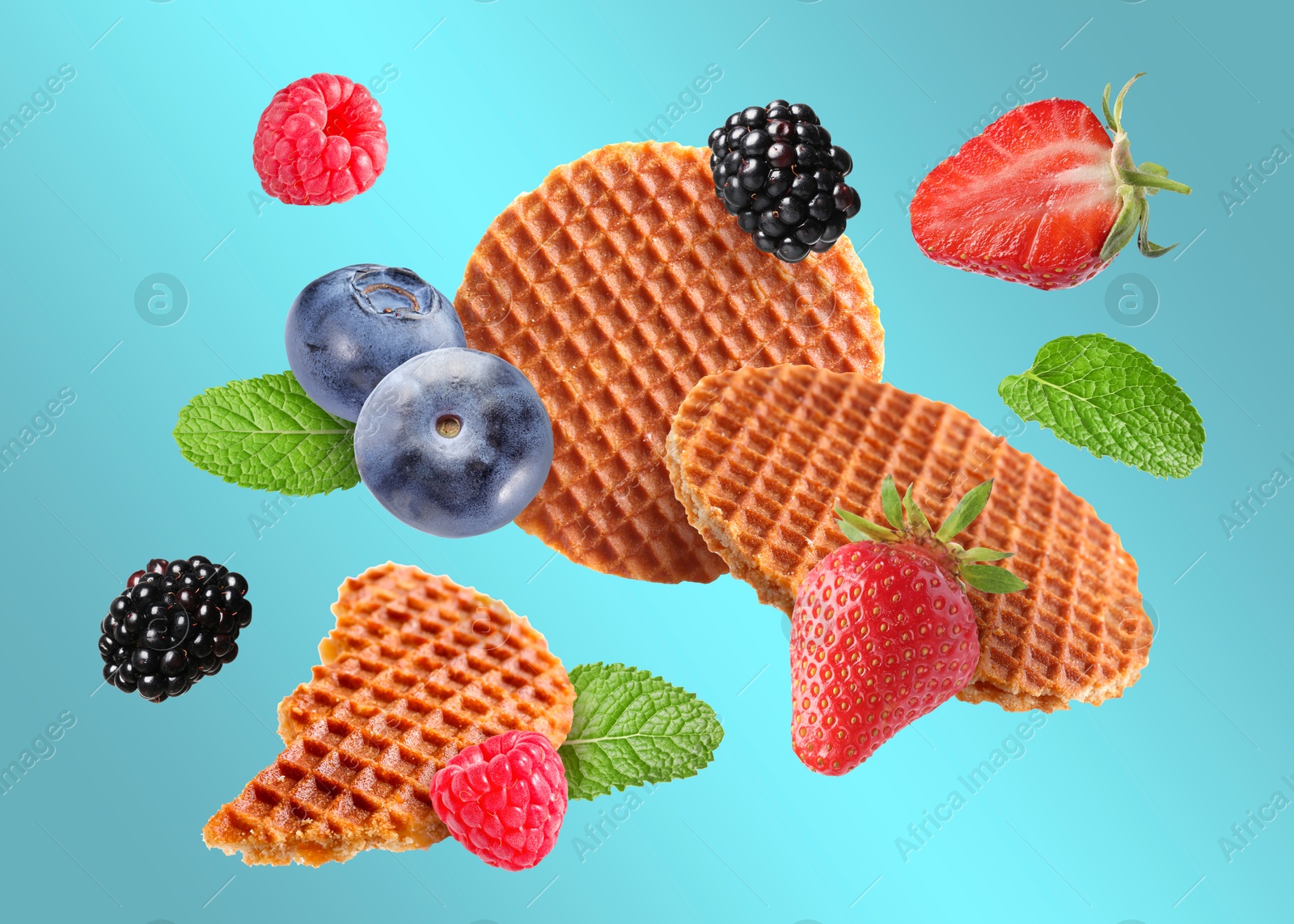 Image of Tasty Dutch waffles, fresh berries and mint flying on light blue gradient background