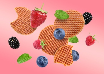 Image of Tasty Dutch waffles, fresh berries and mint flying on pink gradient background
