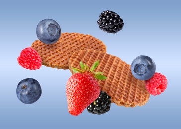 Image of Tasty Dutch waffles and fresh berries flying on blue gradient background