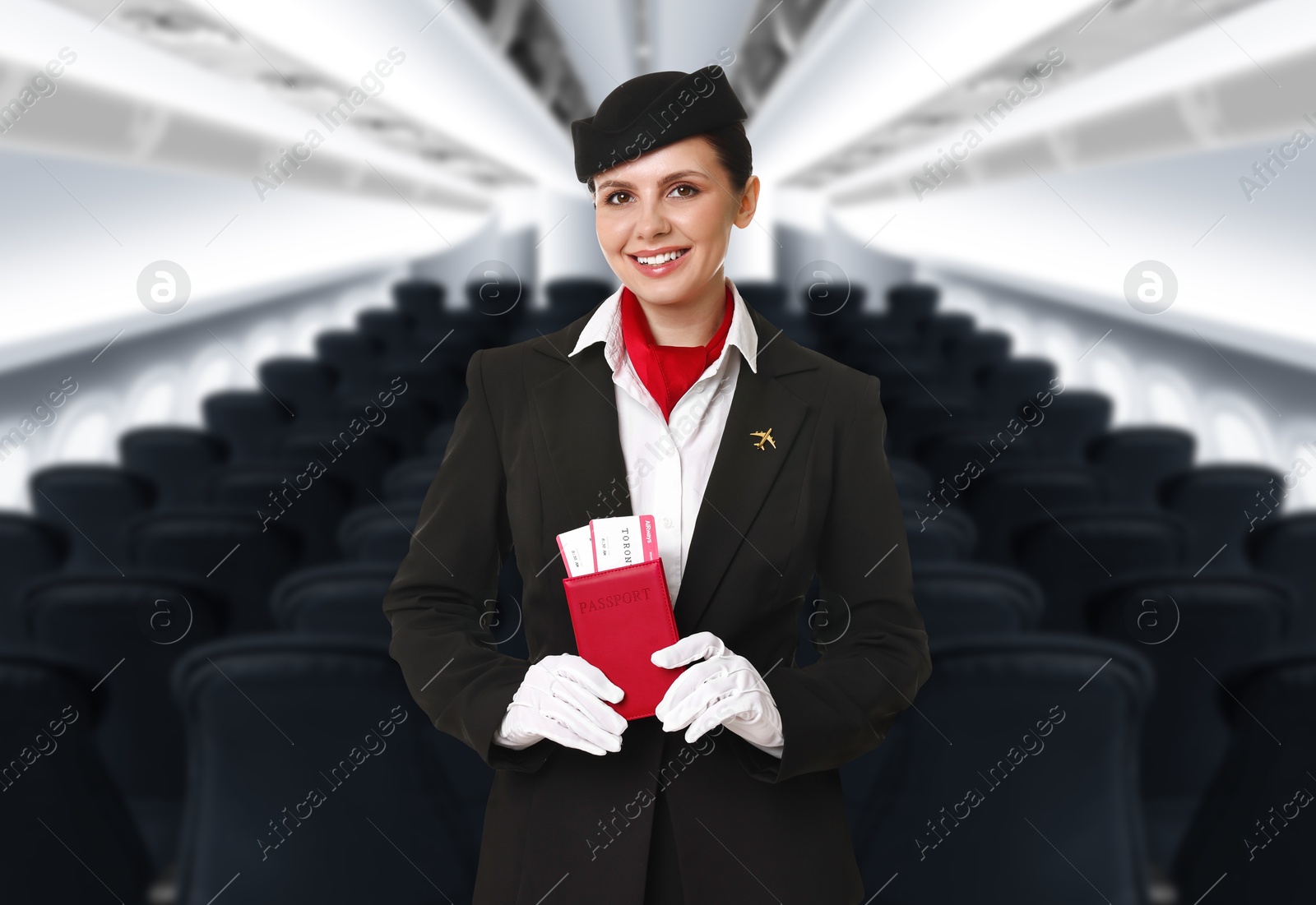 Smiling stewardess holding passport with flight tickets in airplane cabin Image of Smiling stewardess holding passport with flight tickets in airplane cabin