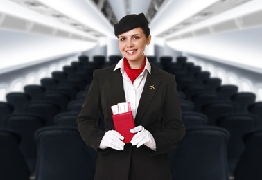 Image of Smiling stewardess holding passport with flight tickets in airplane cabin