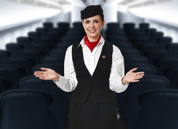 Image of Smiling stewardess demonstrating safety instruction in airplane cabin