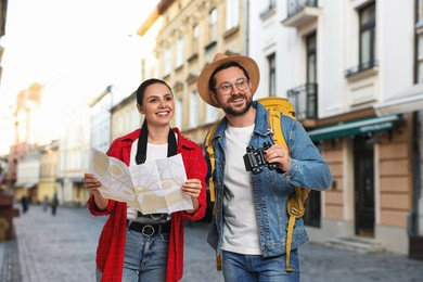 Image of Happy tourists with backpack, map and binoculars on city street