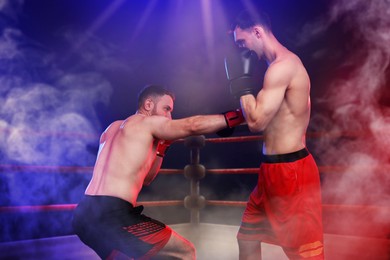 Image of Boxers surrounded by smoke fighting in ring. Sporting event
