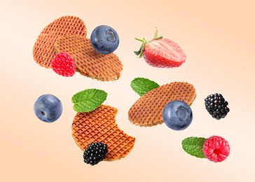 Image of Tasty Dutch waffles, fresh berries and mint flying on beige gradient background